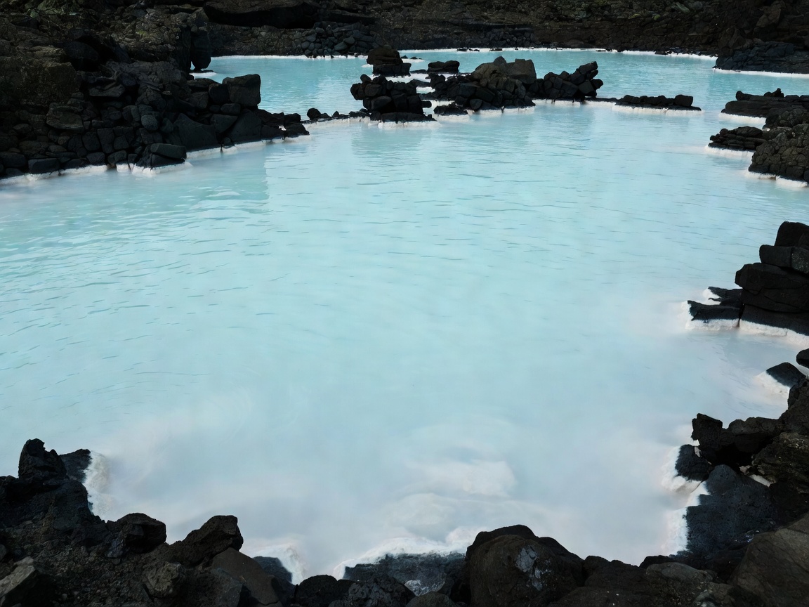 Milky aquamarine silica water framed by black lava stone in Grindavík